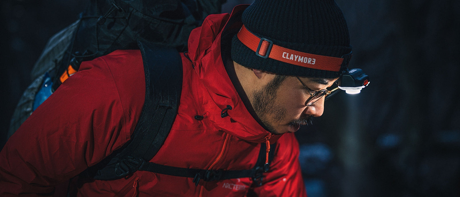 Night hiker navigating in dark woodland with headtorch angled downwards to offer a better view of the trail in front