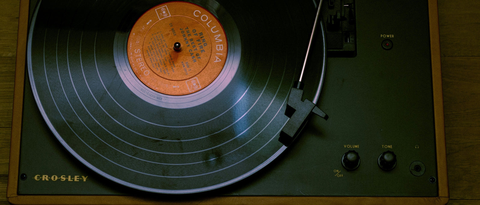 Close-up of a vintage Crosley record player with a Columbia Records vinyl playing, shot from above on a warm wooden surface 