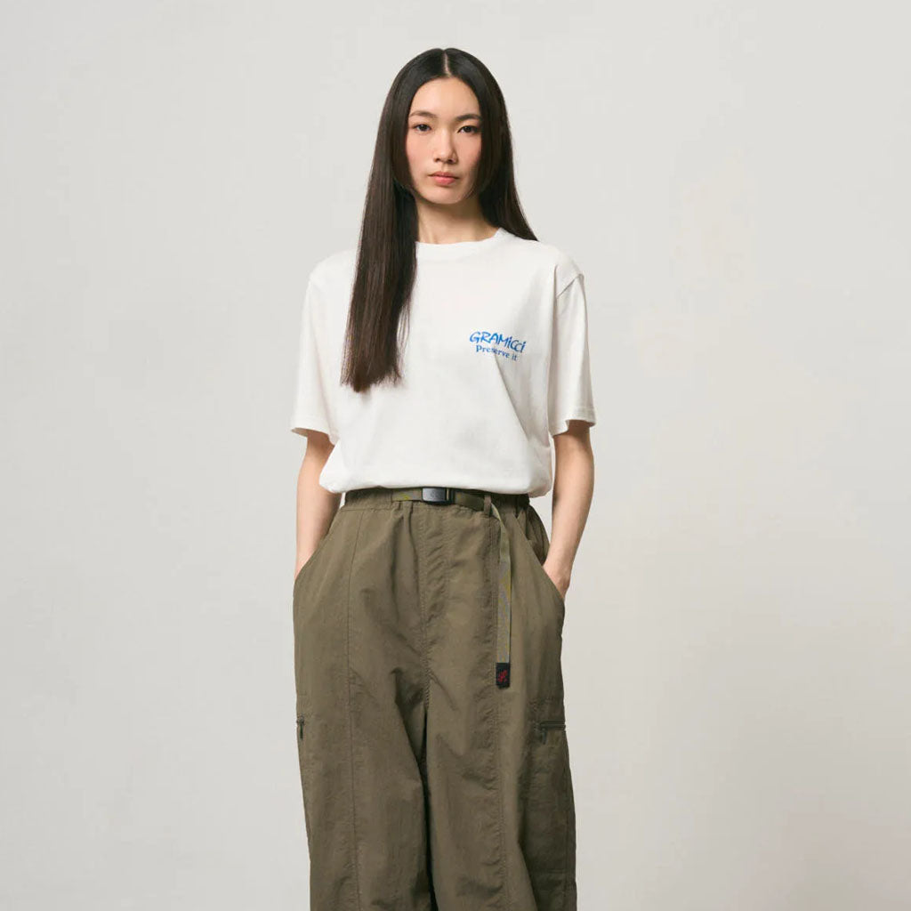Woman wearing Gramicci white logo t-shirt and olive cargo trousers with utility pockets.