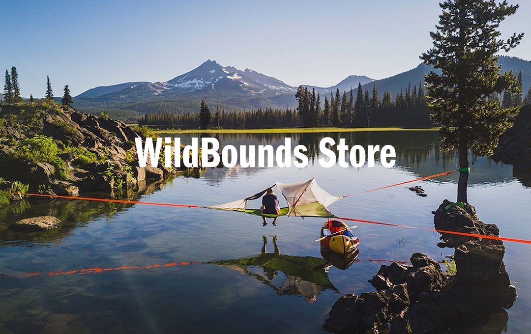 WildBounds Store text overlaid on alpine lake scene with tent, kayaker and snow-capped mountain.